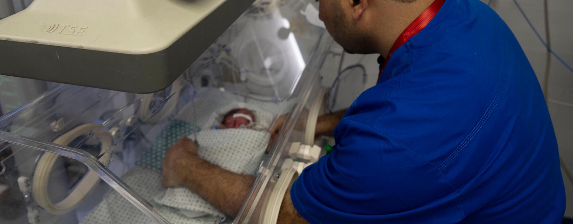 Un miembro del personal del Hospital Al-Helou, en Ciudad de Gaza, Palestina, examina a un recién nacido con bajo peso que se encuentra en una incubadora.