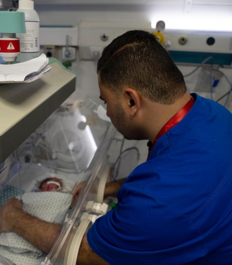 Un miembro del personal del Hospital Al-Helou, en Ciudad de Gaza, Palestina, examina a un recién nacido con bajo peso que se encuentra en una incubadora.