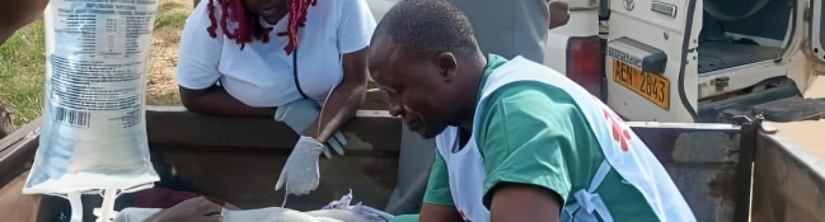 Personal de MSF atiende a un paciente junto a la carretera.
