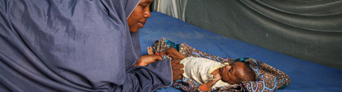 Zulfa'u Musa se inclina mirando a su hija Safiya en el centro de alimentación terapéutica del hospital de Zurmi