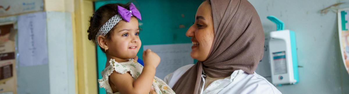 Una trabajadora del personal sanitario de MSF sostiene en brazos a Zahraa, una niña pequeña que recibe atención de seguimiento en el centro de salud Al-Mahdi, en Sadr City, Bagdad.