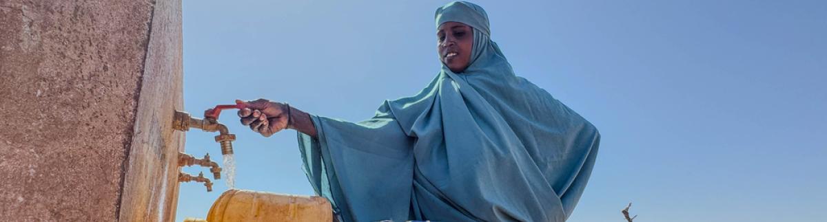 Una mujer llena un bidón en un grifo comunitario del campamento de personas desplazadas de Rasqabobe, en Mudug, Somalia.
