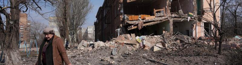 Una mujer camina junto a un edificio dañado por bombardeos en Mariupol, Ucrania. 13 de marzo de 2022.