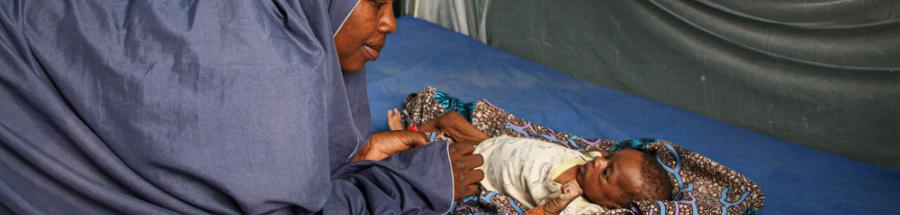 Zulfa'u Musa se inclina mirando a su hija Safiya en el centro de alimentación terapéutica del hospital de Zurmi
