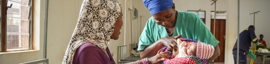 La auxiliar de enfermería Ndayumvire Antoinette sostiene a un bebé mientras habla con la madre en la sala de maternidad del hospital de Médicos Sin Fronteras del campamento de Nduta.