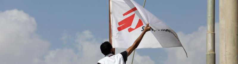 Dos refugiados junto a la bandera de MSF en el campo de Zaatari, en Jordania
