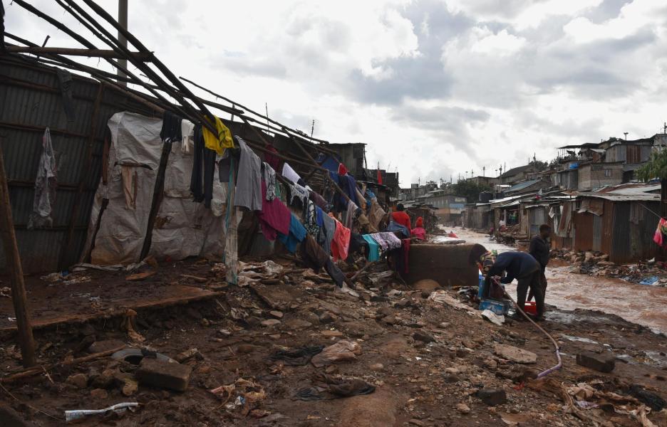 Varias personas lavan la ropa entre sus casas destruidas y el río Mathare tras las inundaciones.