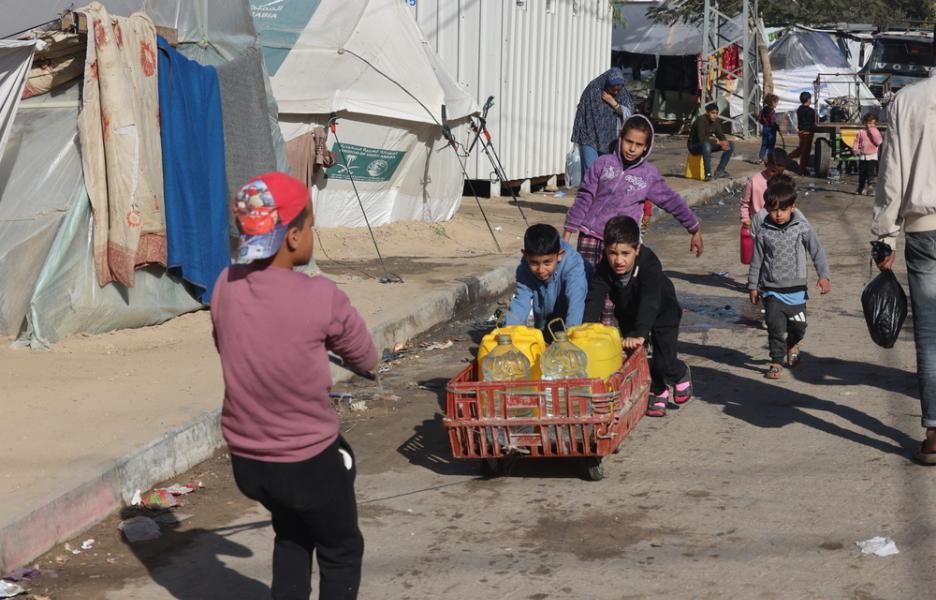 Niños palestinos desplazados llenan sus botellas de agua potable en el barrio de Al-Shaboura, en el sur de Gaza.
