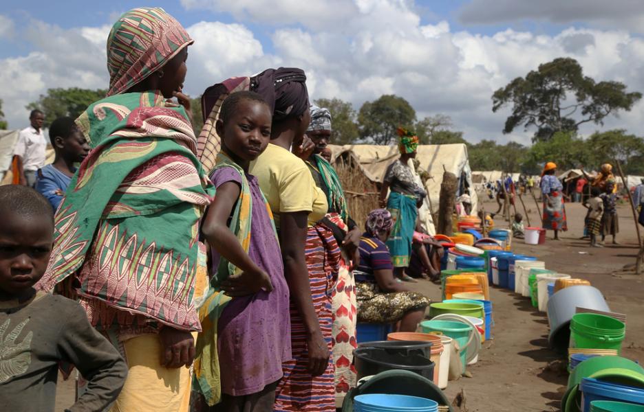 Mujeres y niñas hacen cola en un punto de abastecimiento de agua en el asentamiento Eduardo Mondlane, en Mueda.