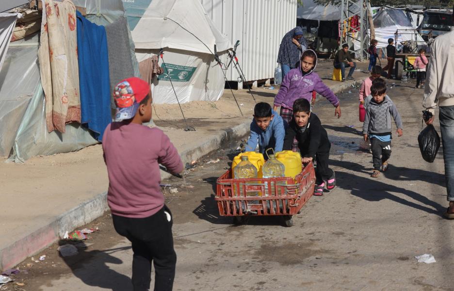 Niños palestinos desplazados llenan sus botellas de agua potable en el barrio de Al-Shaboura, en el sur de Gaza.