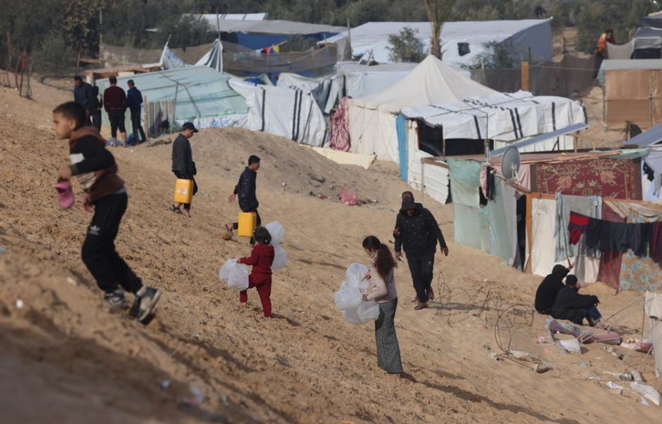 Palestinos desplazados llevan botellas vacías a un camión de agua de MSF en Tal Al-Sultan, un barrio de Rafah.