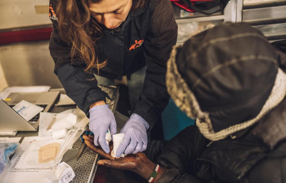 Una de nuestras enfermeras cura la mano de un joven migrante sudanés en Calais.