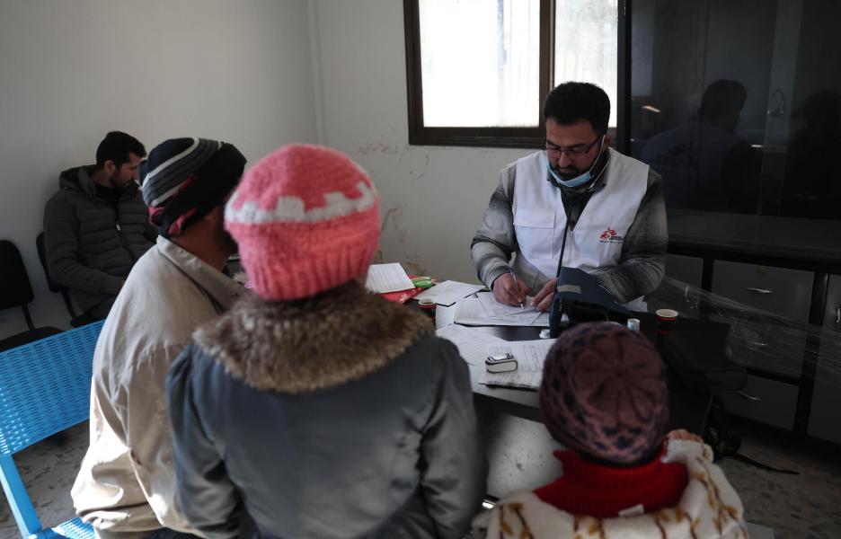 Mohammed Gobasi, trabajador sanitario de MSF, entrega una receta a un padre con dos hijos. 