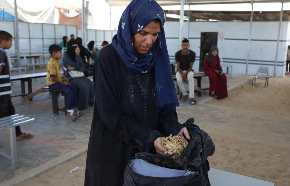 Samah Hamdan, una mujer que ha sido desplazada, recoge algo de pasta para ella y su familia.