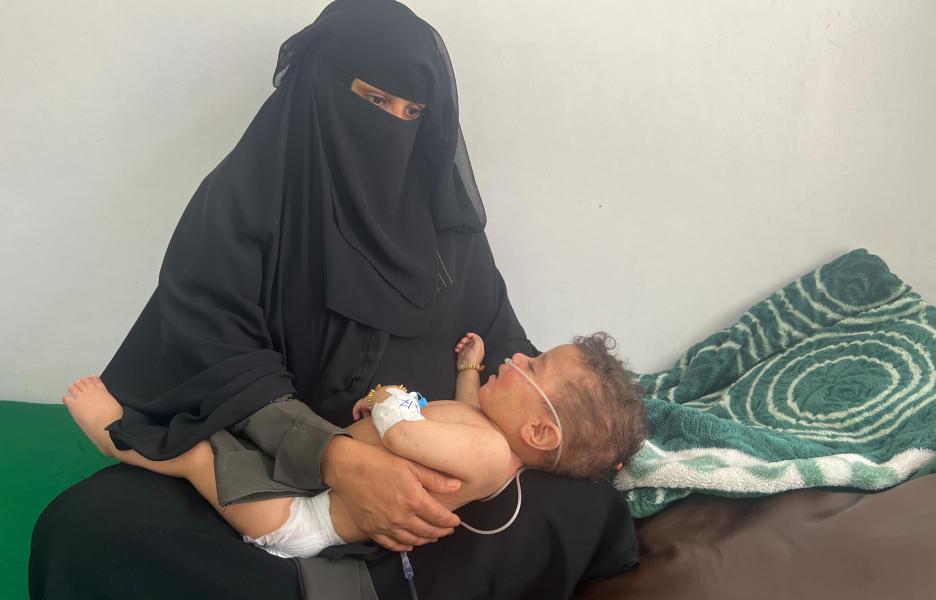 Mas’ool, de diez meses, en brazos de su madre mientras recibe tratamiento en la sala de aislamiento gestionada por MSF en el hospital de Al-Wahda.
