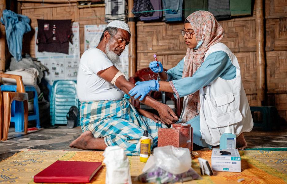 La enfermera de MSF Habiba Jannat Debay saca sangre a Abu Hashim, paciente, para realizar la prueba de detección rápida de la hepatitis C. Campo de personas refugiadas de Kutupalong, en Bangladesh.