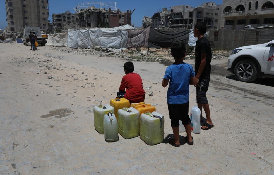 Unos niños esperan junto a sus bidones vacíos a que llegue un camión cisterna en la ciudad de Gaza.