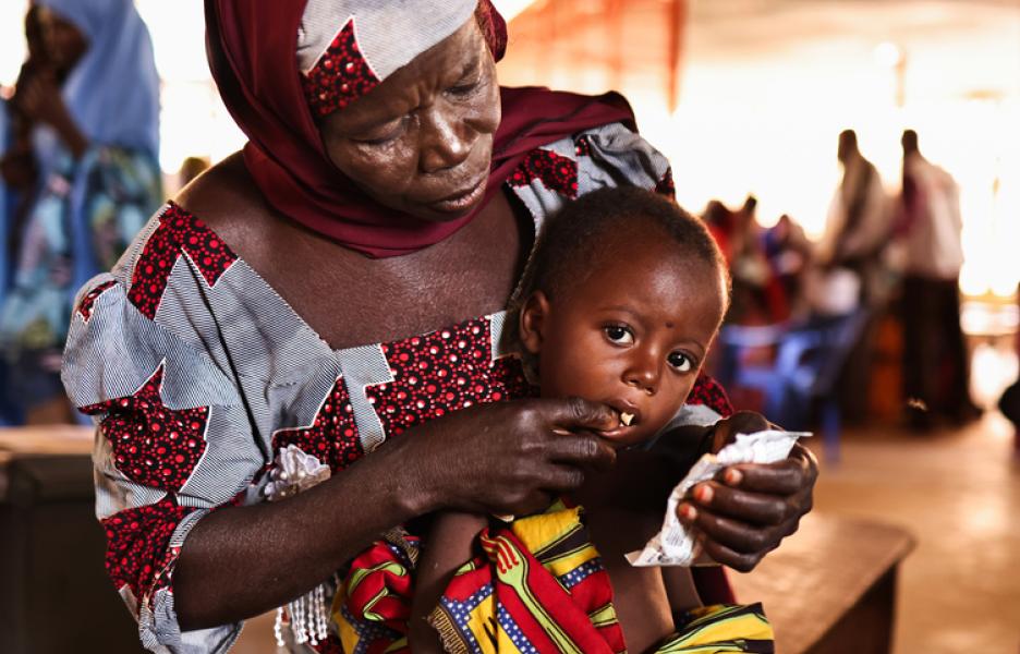 A'i alimenta a su nieto Maniru con un sobre de alimento terapéutico. Desnutrición en Kebbi