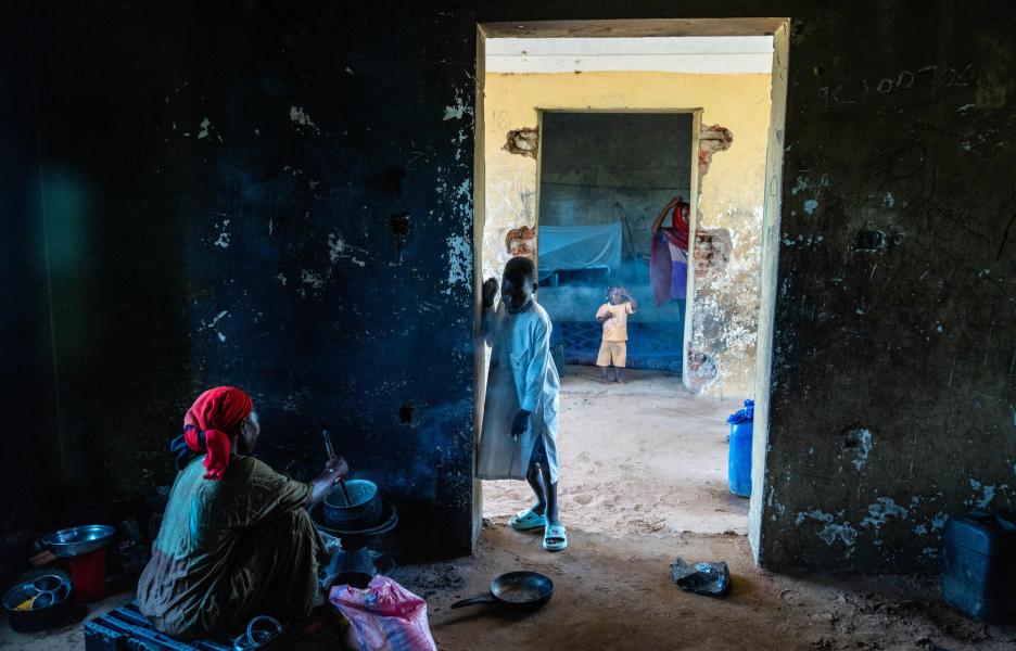 Una mujer cocina en las sombras de un antiguo orfanato en El Geneina.