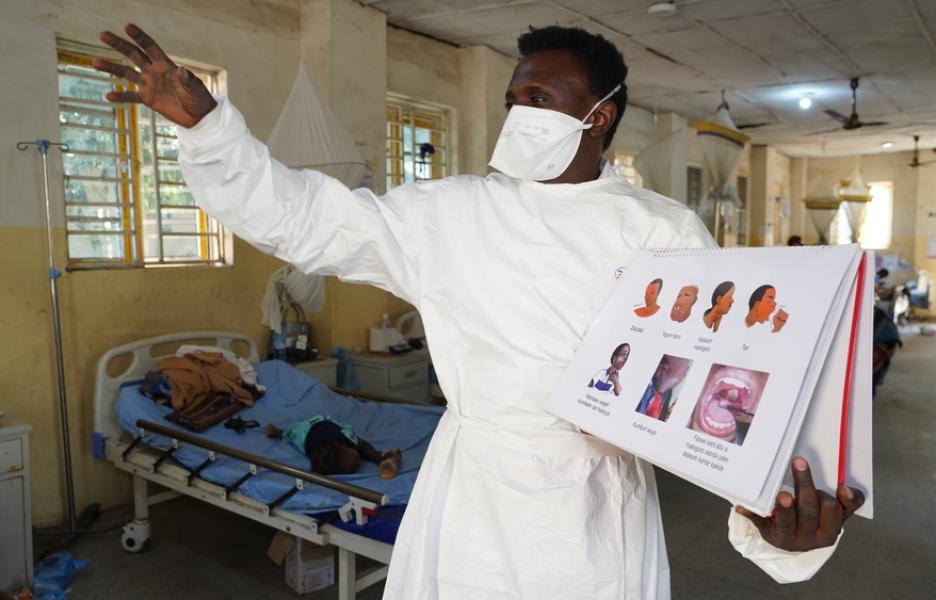 Un agente de promoción de la salud interactúa con pacientes en una sala de difteria. 