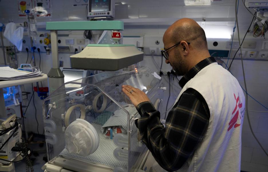 Mohammed Shehada, jefe de nuestras actividades de enfermería en el hospital Al Helou, de Gaza, examina a un recién nacido con bajo peso que yace en una incubadora. 