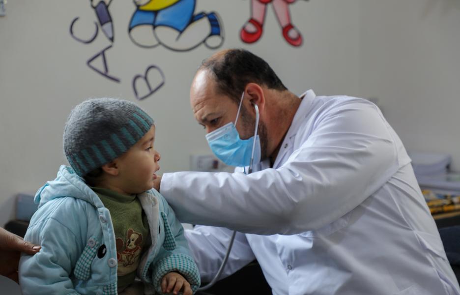 Un médico de la Dirección General de Salud examina a un niño en el centro de atención primaria de Darat Ezza, que cuenta con el apoyo de Médicos Sin Fronteras.  
