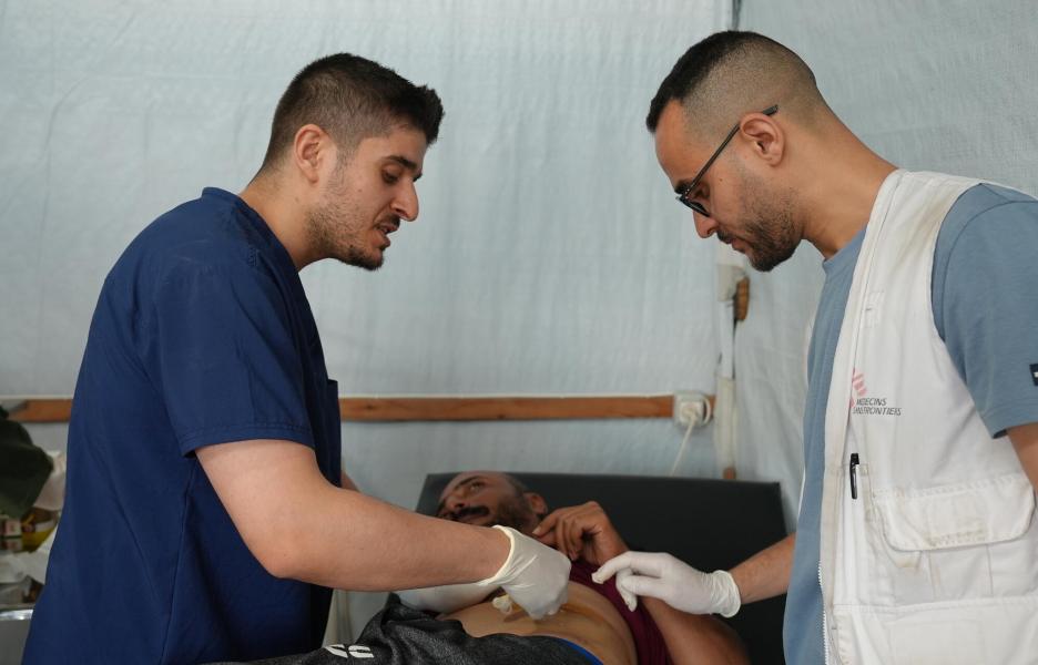 Compañeros de MSF le cambian los apósitos a las heridas de Ashraf.