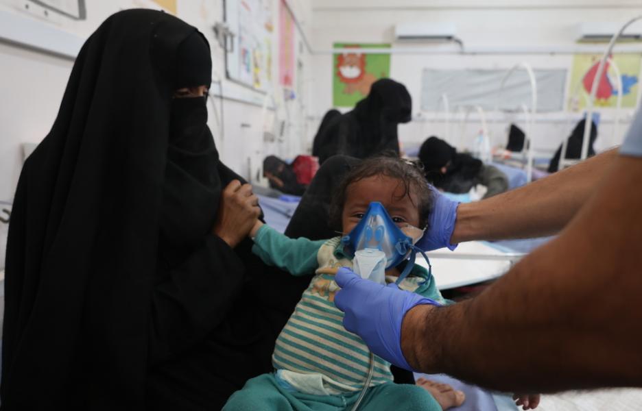 Una madre sostiene a su hijo en brazos mientras el personal médico del Ministerio de Sanidad atiende a un niño en el centro de nutrición terapéutica del Hospital General de Abs, que cuenta con el apoyo de MSF.