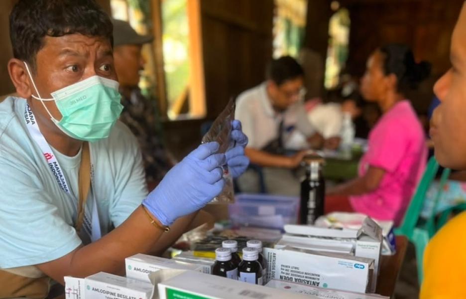 Un miembro del equipo médico de YMSFI explica la medicación a un paciente durante una consulta móvil en el distrito de West Cibal.