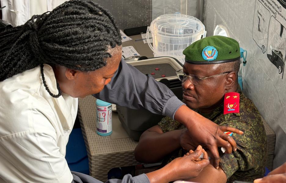 El general de división Gaby Kasongo Mulumba, gobernador de la provincia de Ituri, recibe la vacuna de manos de una enfermera del Ministerio de Sanidad durante la ceremonia de presentación del estudio BRAVO en el Laboratorio Provincial de Salud Pública de Bunia.