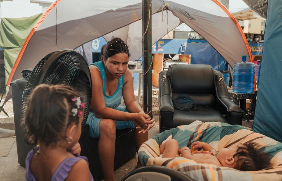 Greydiel Álvarez, de 22 años, habla con su sobrina Greymari Felicia, de 3 años, mientras su hijo Kleiber Capote, de 3 meses, duerme dentro de un campamento provisional en Mare Abajo. La familia vive frente a un complejo habitacional que se derrumbó parcialmente durante los dos terremotos. La Guaira, Venezuela, 23 de septiembre de 2026.