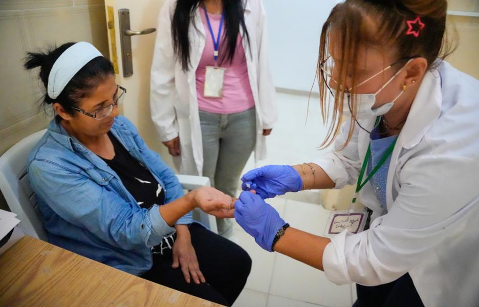 Un miembro del personal de la Dirección de Salud realiza una prueba de glucemia capilar a un paciente en el centro de atención primaria de salud de Al-Qutaylibiyah.
