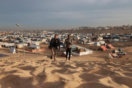 Dos palestinos caminan sobre una duna cerca de un campamento informal de personas desplazadas en la zona costera de Mawasi Rafah