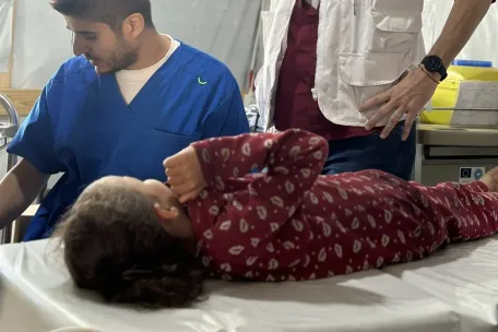 Rúa, de 6 años, herida por una bala que le rozó la cabeza, en la cínica de Médicos Sin Fronteras en Al Mawasi, junto a Paulo Milanesio, coordinador de MSF en Gaza. 