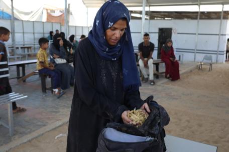 Samah Hamdan, una mujer que ha sido desplazada, recoge algo de pasta para ella y su familia.