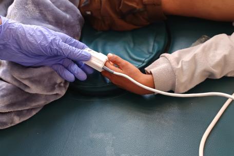 Una enfermera registra los signos vitales de un paciente con sarampión 