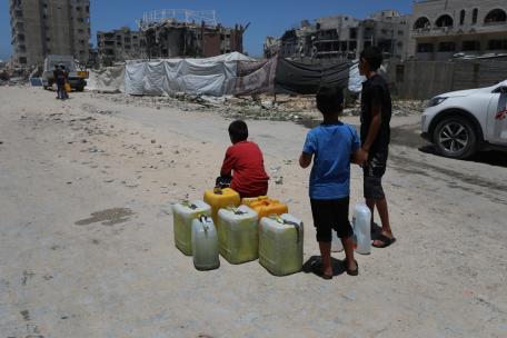 Unos niños esperan junto a sus bidones vacíos a que llegue un camión cisterna en la ciudad de Gaza.