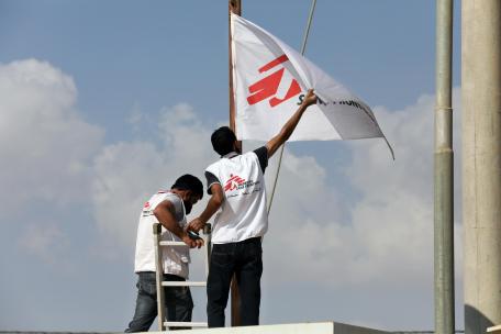 Dos refugiados junto a la bandera de MSF en el campo de Zaatari, en Jordania