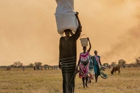 Una mujer lleva bolsas de comida en la cabeza tras un lanzamiento aéreo del PMA cerca de Chuil, en el estado de Jonglei, Sudán del Sur.