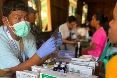 Un miembro del equipo médico de YMSFI explica la medicación a un paciente durante una consulta móvil en el distrito de West Cibal.