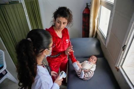 Una doctora examina a un bebé en el centro de atención primaria de salud de Al-Qutaylibiyah