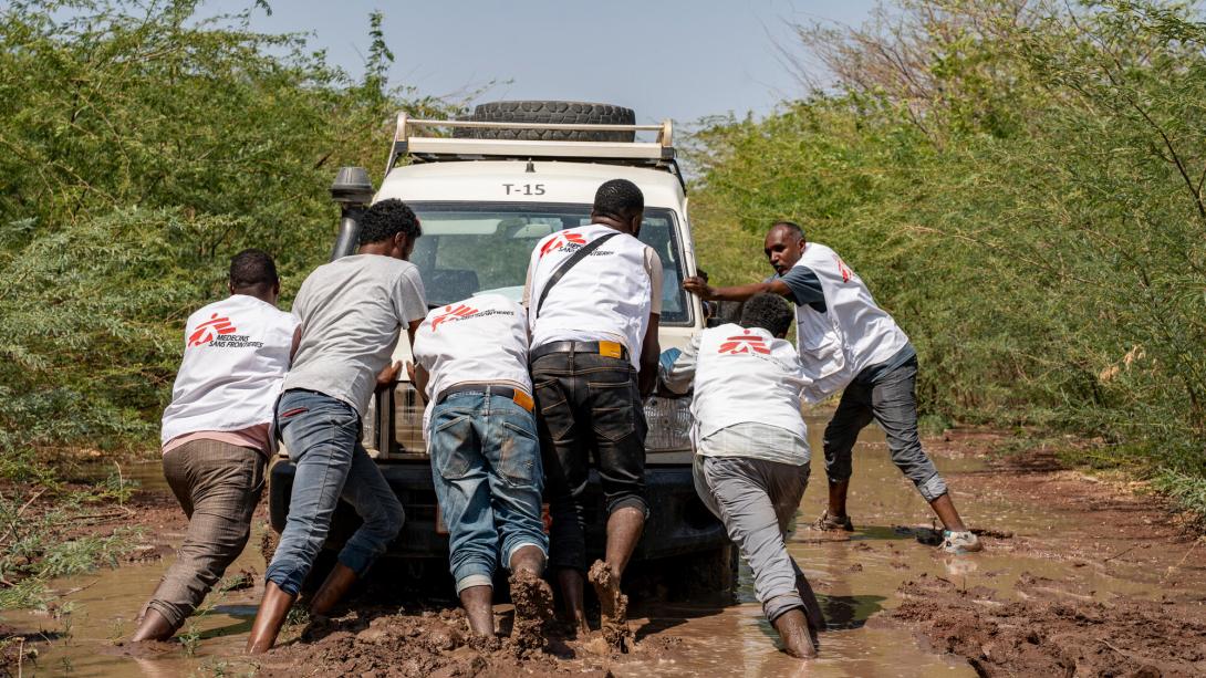 Personal de MSF empujando un vehículo atascado en el barro.