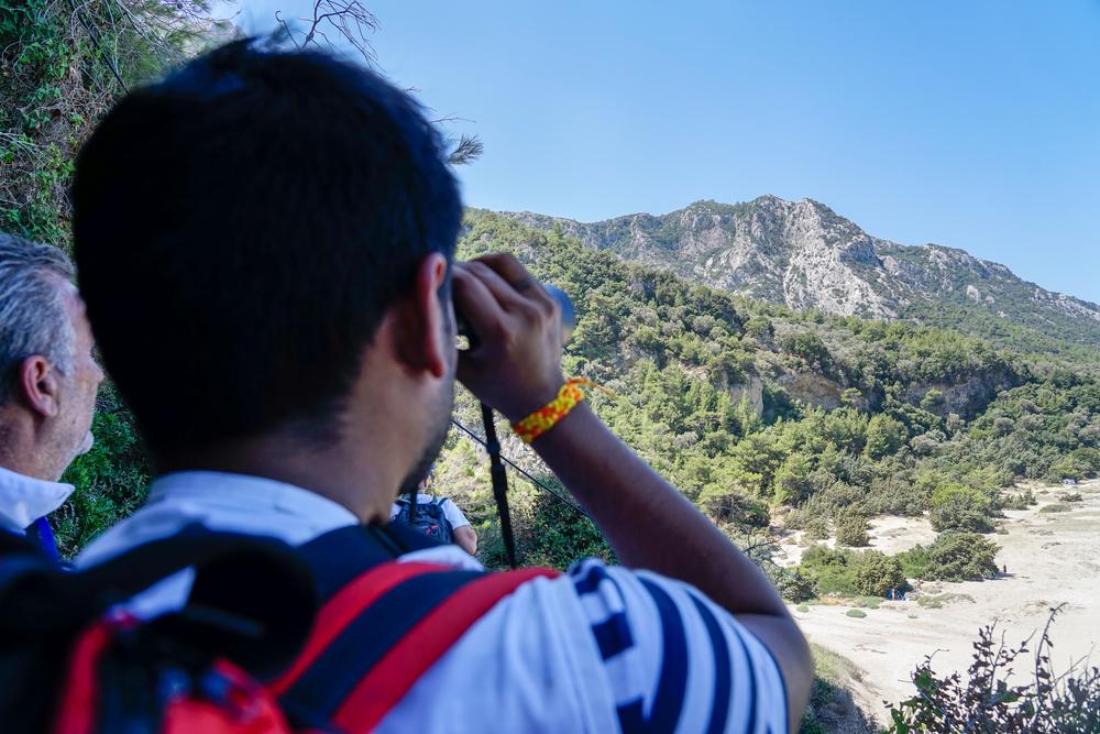 Un miembro de MSF busca en el bosque con los prismáticos durante una respuesta médica de emergencia en la isla de Samos, Grecia. Un miembro de MSF busca en el bosque con los prismáticos durante una respuesta médica de emergencia en la isla de Samos, Grecia.