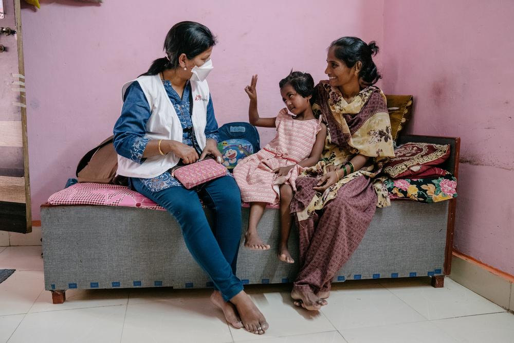  Vaishnavi, una paciente de siete años de tuberculosis resistente a los medicamentos interactúa con Prachi, enfermera de MSF desde el regazo de su madre.