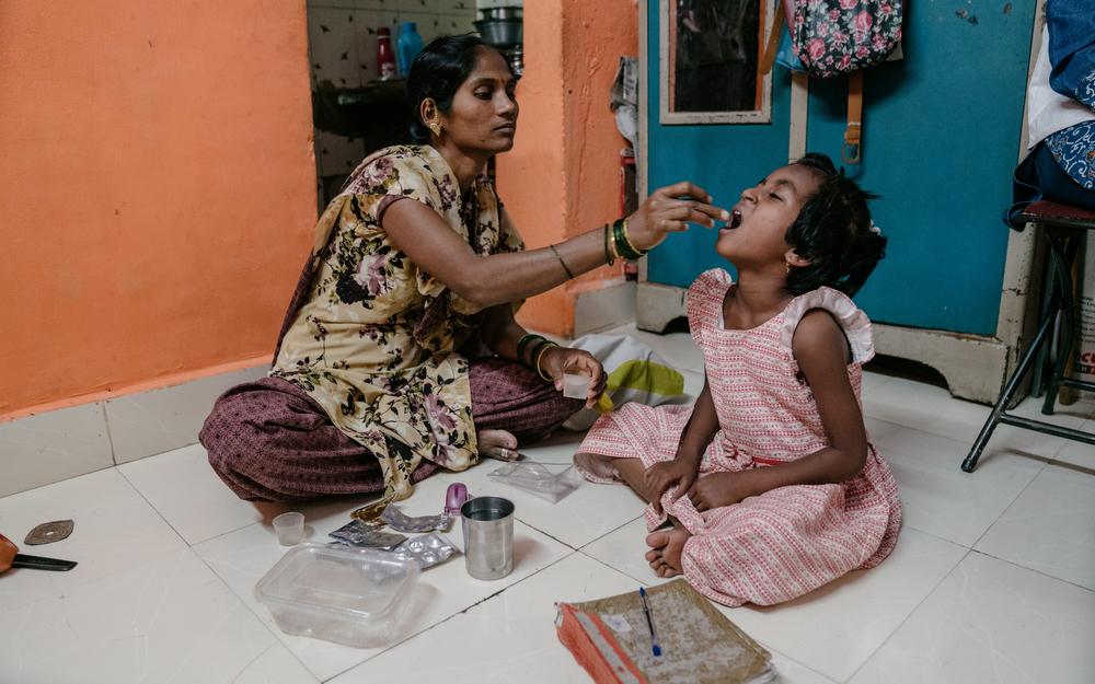 Vishakha le da las medicinas para la tuberculosis resistente a los medicamentos a su hija Vaishnavi.