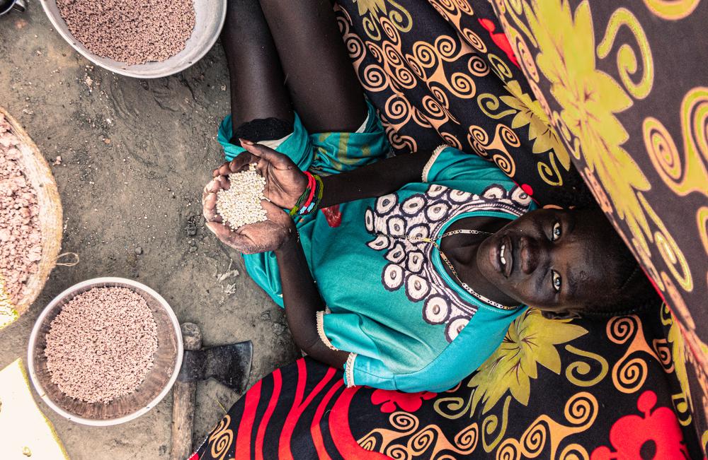 Una mujer joven clasifica grano en su refugio en la ciudad de Bentiu.