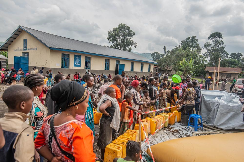 Personas desplazadas hacen cola para conseguir el agua potable para sus familias.