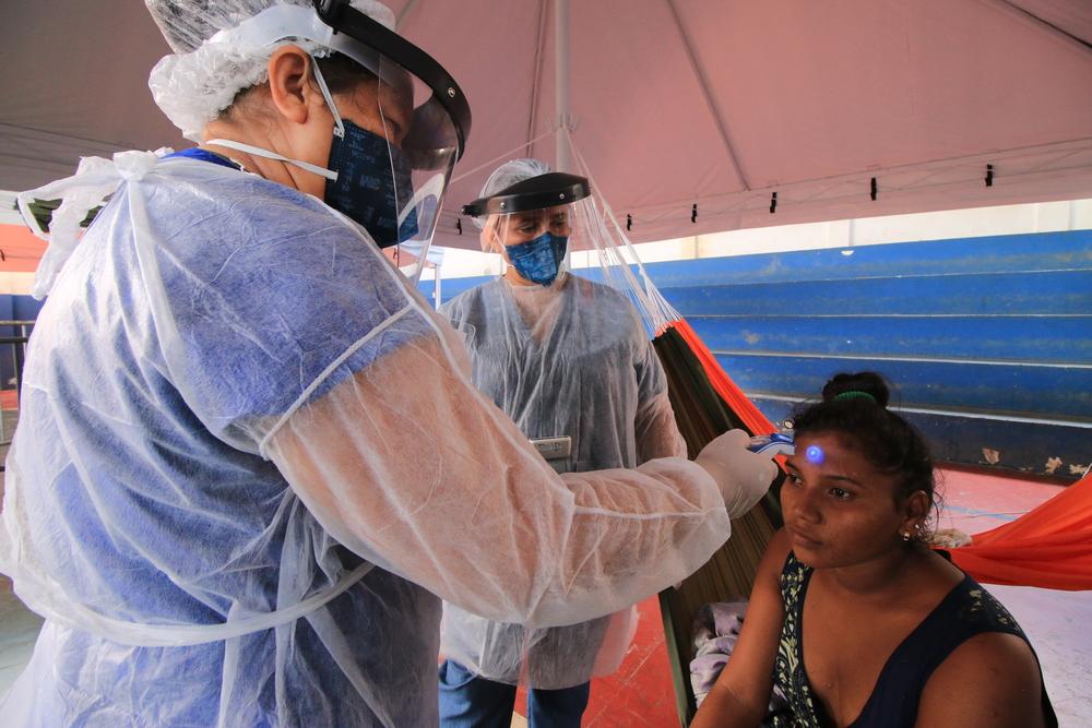 Nuestro compañero toma la temperatura a una mujer warao en un centro de observación y aislamiento. Manaus, Amazonia.